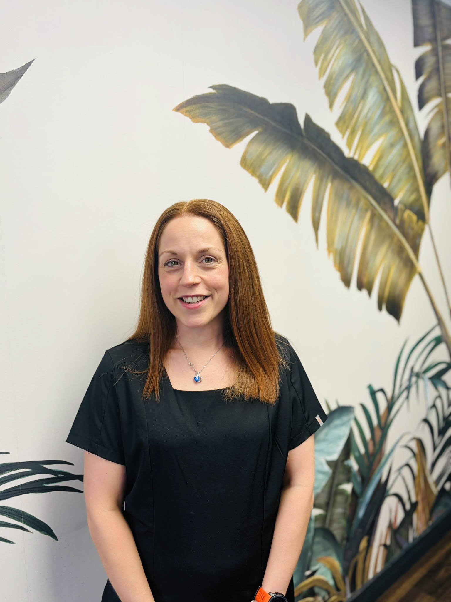 Picture of Helen stood in front of a wall with palm tree image